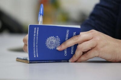 Dois contracheques de empresas diferentes sobre a mesa, ao lado de uma calculadora, representando o INSS de quem tem dois empregos