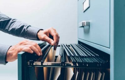 Pastas de documentos ao lado de um notebook digitalizando papéis, ilustrando o prazo de guarda de documentos da empresa